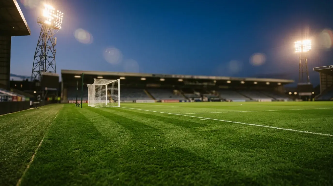 Vue du terrain d'un stade de Premier League en soirée avec projecteurs allumés